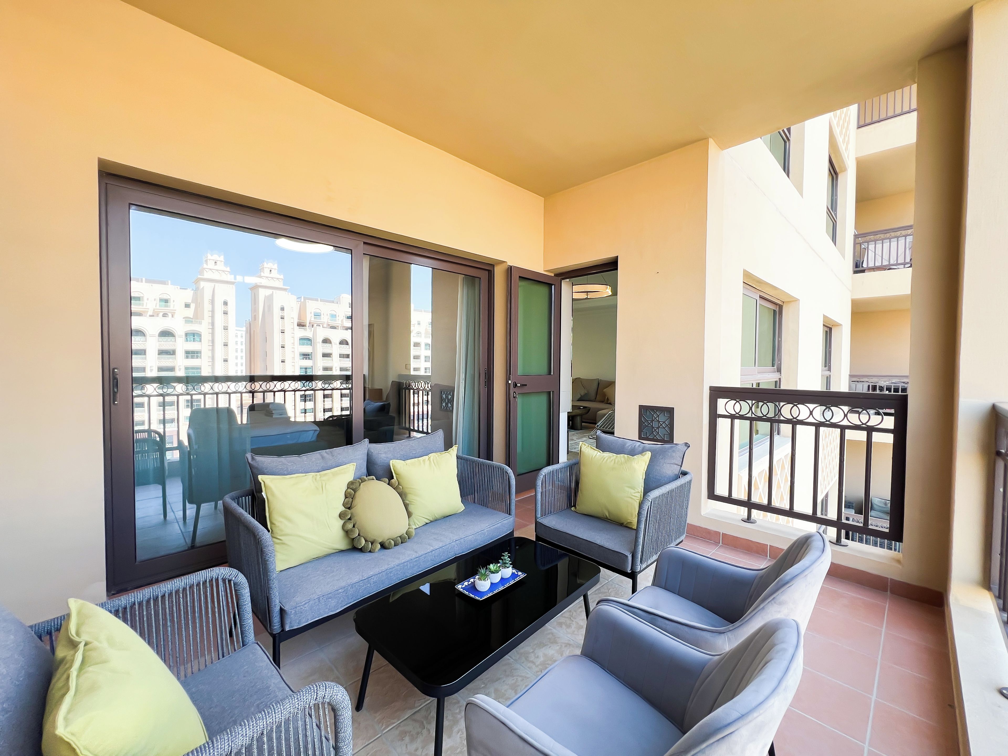 Un balcon avec un canapé, des chaises et une table basse.