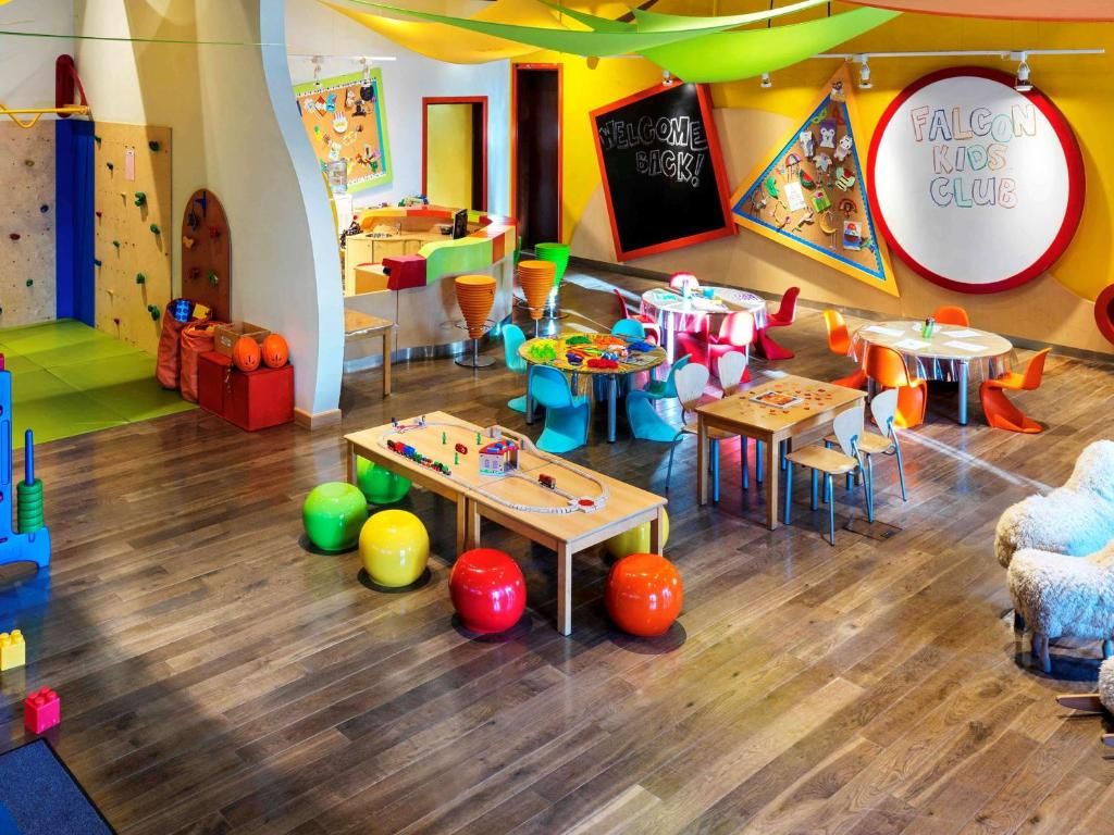 Un espace de jeux pour enfants avec des murs d’escalade, des tables et des sièges colorés.