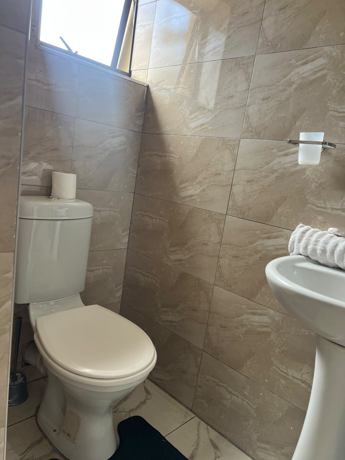 Un bagno con il water, un lavandino e un portasciugamani.