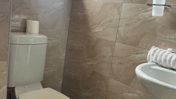 Un bagno con il water, un lavandino e un portasciugamani.