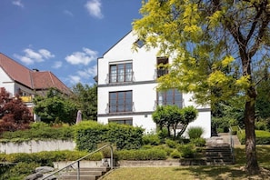 A two-story building with a white facade, multiple windows, and a staircase leading to the entrance. - La Perla - Longing for the Sea (Überlingen)