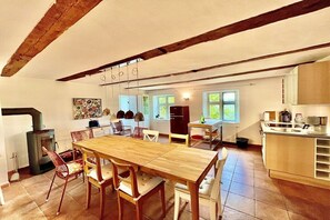 Eine geräumige Küche mit Holztisch und -stühlen, einem eingebauten Backofen und einem Fenster mit Blick auf eine grüne Landschaft.