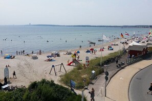A beach with people swimming and sunbathing, tents, and a playground. - Holiday apartment with 1 bedroom (Sierksdorf)