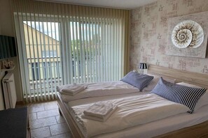 Una cama doble con almohadas a rayas, una mesita de noche con una lámpara y una pared con papel tapiz de temática náutica.