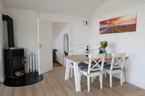 A room with a fireplace, a dining table with chairs, a painting on the wall, and a door leading to another room. - Holiday home in Kappeln with swimming pool (Kappeln)