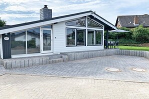 Una casa moderna con un portico coperto, ampie finestre e un camino.