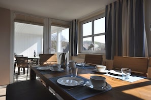 En matplats med ett bord dukat för två personer, en kaffebryggare och utsikt genom fönstret.