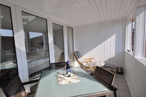 A sunlit patio with a table, chairs, and a bottle of wine. - Holiday apartment in Binz with swimming pool (Binz)