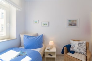 A bedroom with a bed, a nightstand with a lamp, and two framed pictures on the wall. - Holiday apartment in Binz with swimming pool (Binz)