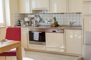 A kitchen with a built-in oven, a coffee maker, and a variety of fruits on the counter. - Holiday apartment in Binz with swimming pool (Binz)