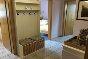 Habitació amb una panca integrada amb espais d'emmagatzematge, un penjador i un llit al fons.