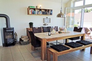 Ein gemütliches Wohnzimmer mit einem Holztisch, Stühlen, einem Bücherregal und einem Kamin.