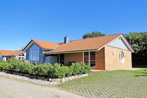 A two-story house with a red-tiled roof, a brick exterior, and a small circular window on the side. - Luxury holiday home lighthouse (Bohnert)