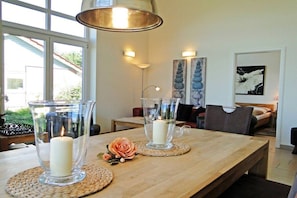 Een eetruimte met een houten tafel, transparante kandelaars en geweven placemats.