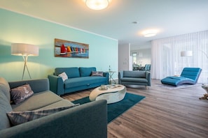 Ein modernes Wohnzimmer mit einer Couch, Sesseln, einem Couchtisch und einem Bild an der Wand.