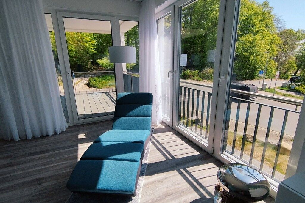 A balcony with a blue sofa, a lamp, and a grill.