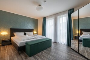 A modern hotel room with a large bed, a green upholstered bench, a nightstand with a lamp, and a large mirror on the wall. - Holiday apartment with 2 bedrooms (Sassnitz)