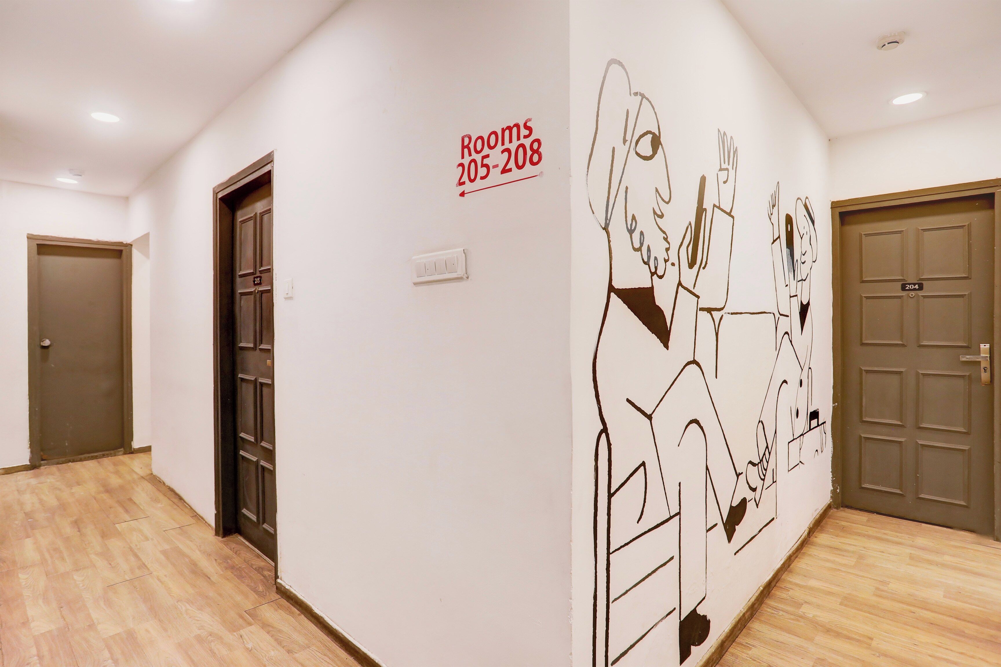 A hotel corridor with wooden flooring, doors numbered 205 and 208, and a wall mural.