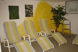 Une pièce comprenant quatre fauteuils à rayures, une plante en pot et une étagère en métal.