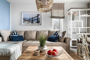A living room with a beige sofa, a wooden coffee table, and a white bookshelf. - Holiday apartment at the marina (Damp)