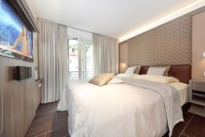 Een hotelkamer met een groot bed, een televisie aan de muur en uitzicht op het landschap door een schuifdeur.