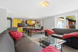 A modern living room with a sofa, a glass coffee table, and a dining area with a table and chairs. - Holiday home in Wieck/Darß with sauna (Wieck\/Darß)