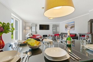 A dining area with a table set for two, a bottle of champagne, and a bowl of snacks. - Holiday home in Wieck/Darß with sauna (Wieck\/Darß)