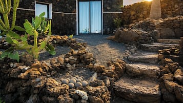 A stone building with a cactus garden and a palm tree.