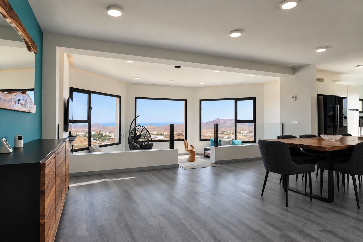 Un interior moderno con comedor, ventanas amplias y vistas al paisaje.