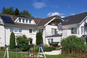 Ein zweistöckiges Wohnhaus mit Balkon, Solaranlage und einem gepflegten Garten.