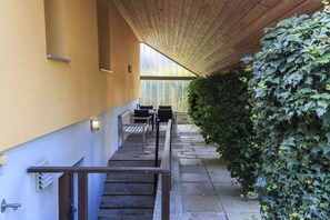 A covered outdoor area with a staircase leading to a seating area, surrounded by greenery. - Holiday home with 3 bedrooms (Born a. Darß)