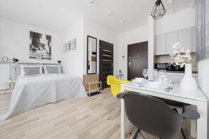 Ein modernes Hotelzimmer mit Bett, Schreibtisch, Stuhl und einer Küchenzeile.