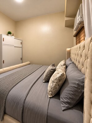 A bedroom with a bed, pillows, a bedside table, and a wardrobe. - Deluxe Modern 3Bedroom Suite in Ermita Manila PH (Manila)