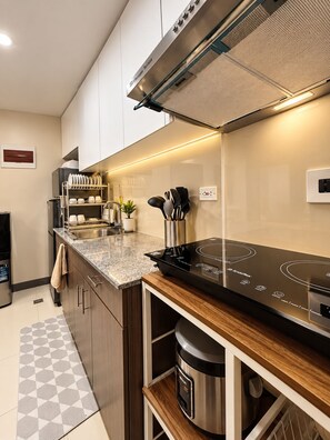 A modern kitchen with a built-in stove, a dish rack, and a small plant. - Deluxe Modern 3Bedroom Suite in Ermita Manila PH (Manila)