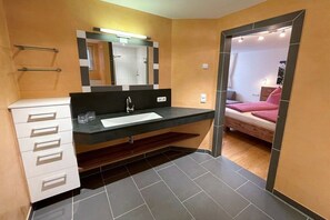 A modern bathroom with a dark countertop sink, a mirror, and a white cabinet.