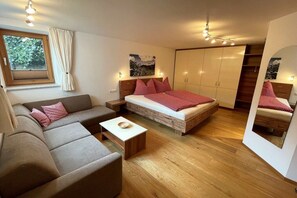 Een moderne slaapkamer met een bed, een bank en een kledingkast.