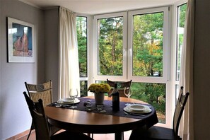 A dining area with a round table, chairs, a vase of flowers, and a bottle of wine. - Apartment in Baabe with balcony and Wi-Fi (Baabe)