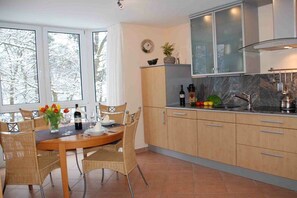 A modern kitchen with a dining area, large windows, and a view of trees. - Apartment in Baabe with balcony and Wi-Fi (Baabe)
