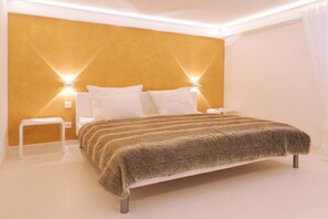 Een moderne slaapkamer met een groot bed, twee nachtkastjes en wandlampen.