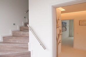 A staircase with a metal handrail leading to a room with a door. - Holiday apartment with 1 bedroom (Timmendorfer Strand)
