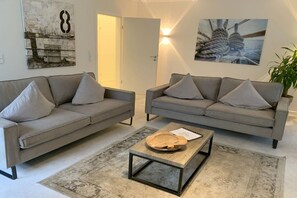 A modern living room with two grey sofas, a coffee table, and a rug. - Holiday apartment with 1 bedroom (Timmendorfer Strand)