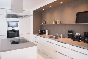 A modern kitchen with built-in appliances, a countertop, and a wall-mounted shelf. - Holiday apartment with 1 bedroom (Timmendorfer Strand)