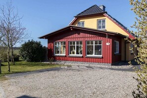 Una casa roja y amarilla con camino de grava y cielo despejado.