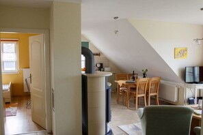 A room with a dining table, chairs, a television, and a fireplace. - Holiday apartment with 2 bedrooms (Wieck a. Darß)