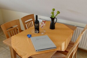 Ett matbord med en bok, en flaska, ett glas och en vas med blommor.