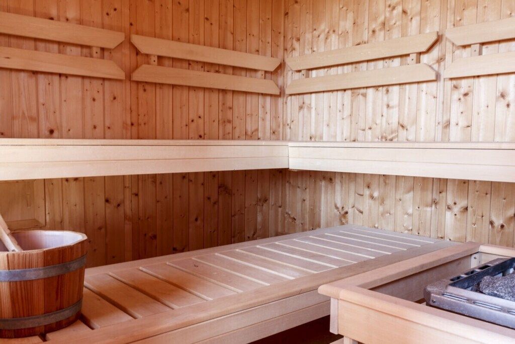 Un sauna avec des murs en bois et un banc.