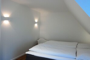 Ein Schlafzimmer mit einem Bett, weißen Wänden und zwei Wandleuchten.