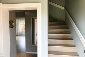 A staircase with wooden steps and a white handrail, leading to a room with a door and a window with curtains. - View of the dike in Nieblum (Nieblum)