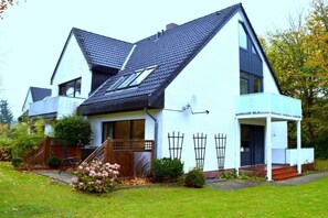 A two-story house with a sloped roof, a covered porch, and a well-maintained garden. - Waldstrasse - Holiday Apartment 26 (Wyk auf Föhr)