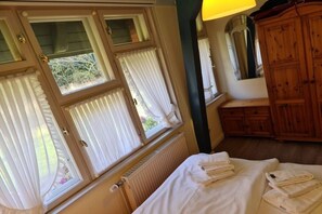 Ein Zimmer mit einem Bett, einem Holzschrank und einem Fenster mit Vorhängen.